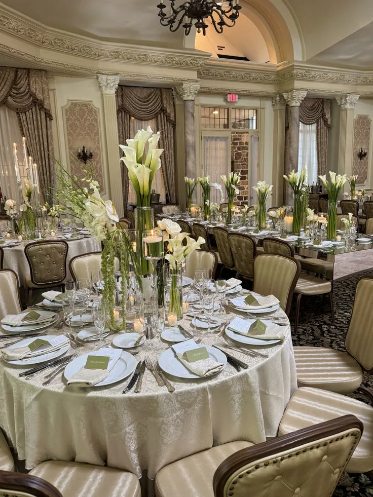 A ballroom table styled with tall calla lilies, candlelight and gold place settings